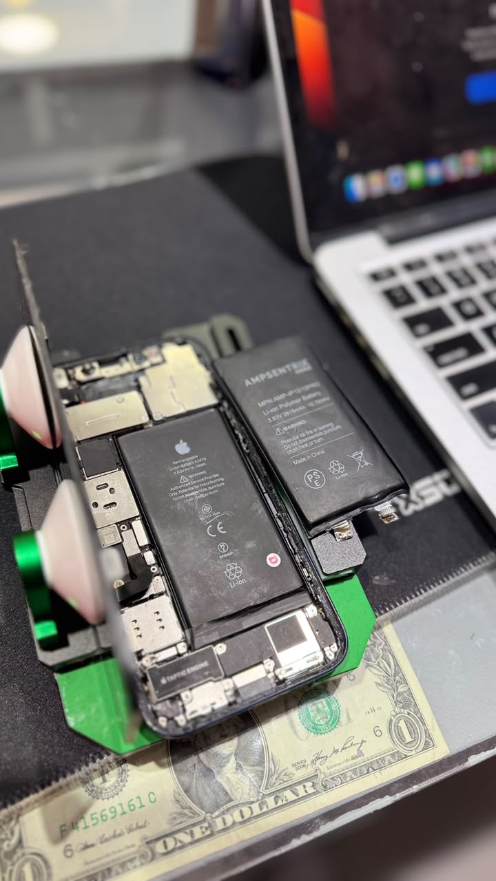 Revisión de batería y componentes de un celular junto a una notebook